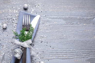 Photo of Cutlery set on grey wooden table, top view with space for text. Christmas celebration