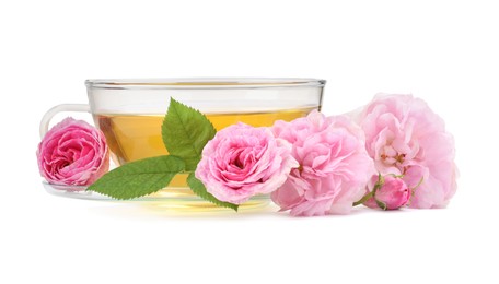 Photo of Aromatic herbal tea in glass cup, flowers and green leaves isolated on white