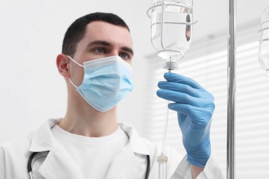 Photo of Doctor setting up IV drip in hospital, selective focus
