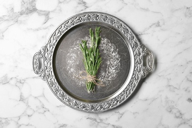 Photo of Plate with rosemary on marble background, top view. Aromatic herbs