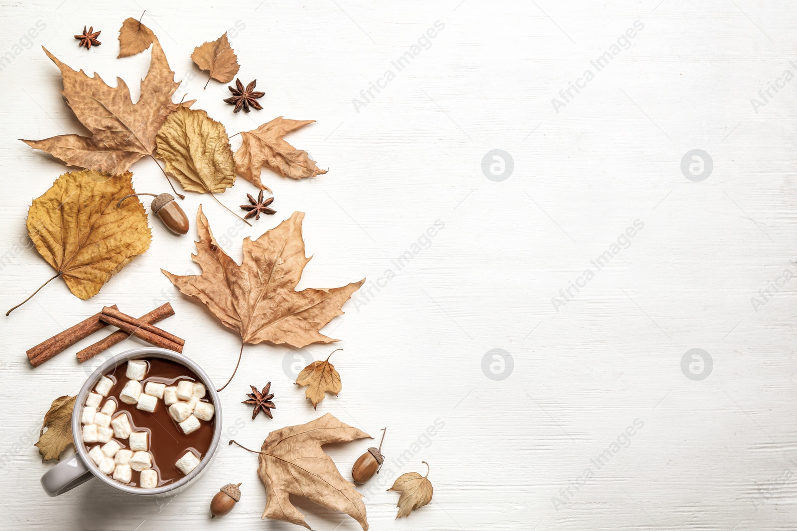 Photo of Flat lay composition with cup of hot drink and autumn leaves on white wooden table, space for text. Cozy atmosphere