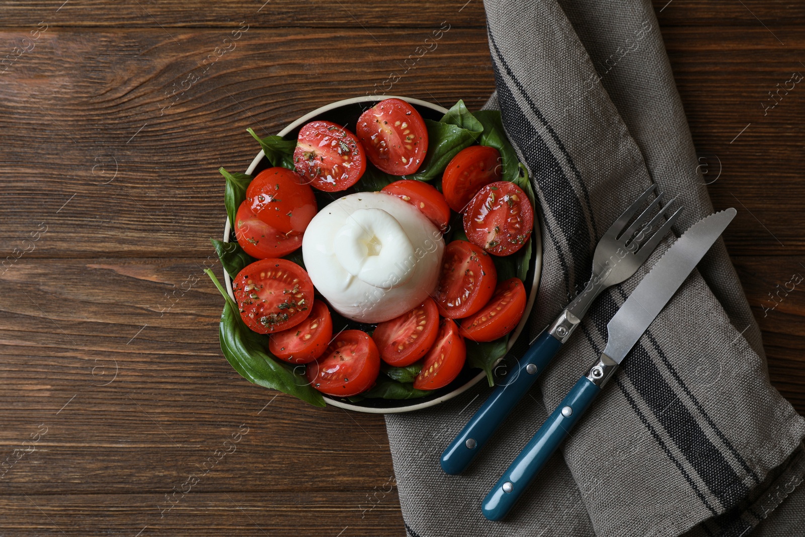 Photo of Delicious burrata cheese with tomatoes and basil served on wooden table, flat lay