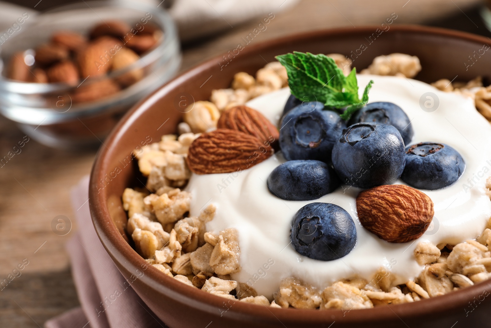Photo of Bowl of tasty oatmeal with blueberries and yogurt on table, closeup