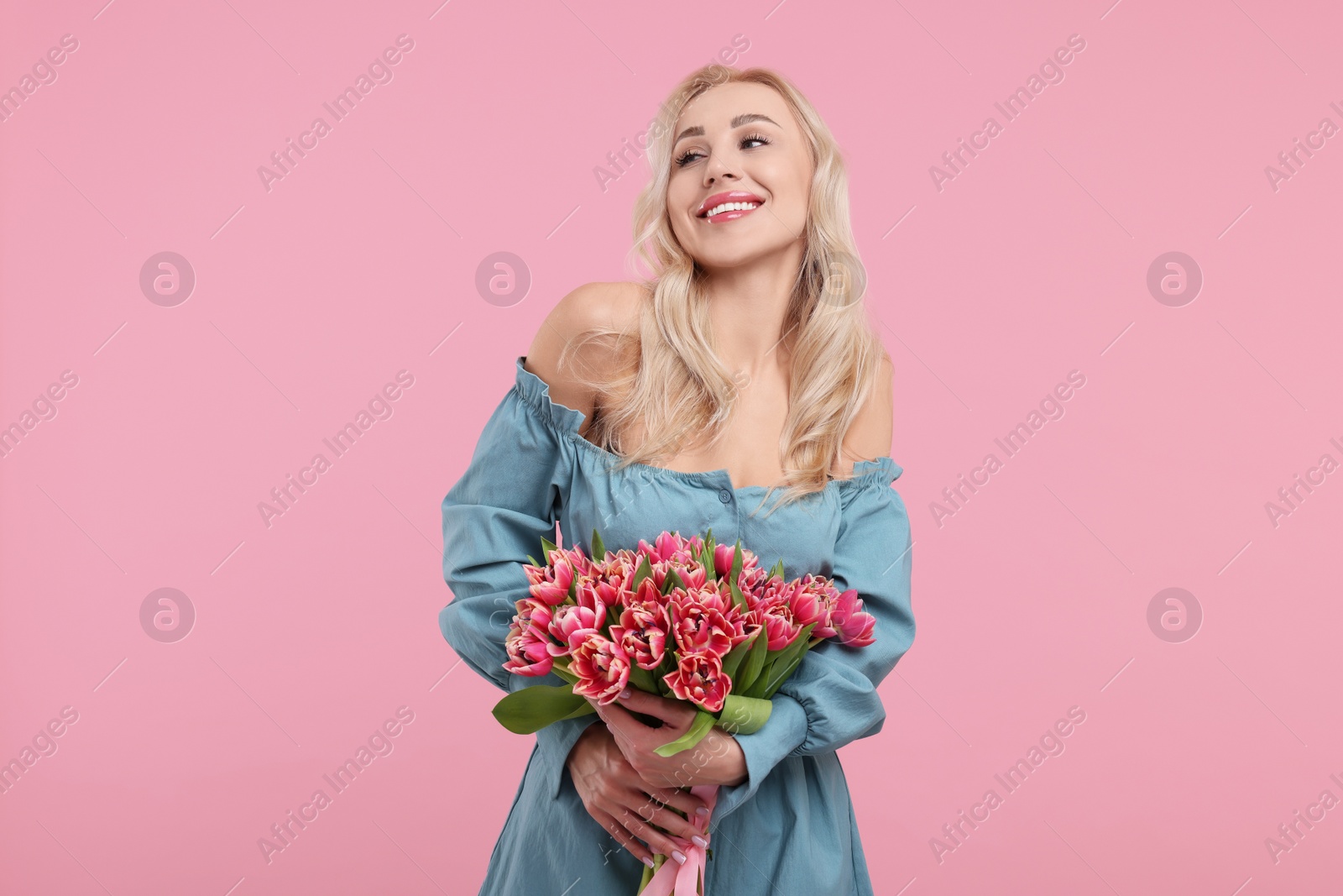 Photo of Happy young woman with beautiful bouquet on dusty pink background