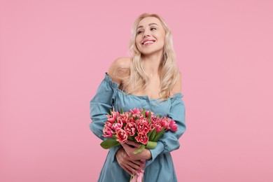 Happy young woman with beautiful bouquet on dusty pink background