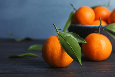 Photo of Fresh ripe tangerines with green leaves on table. Space for text