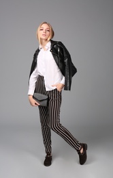 Photo of Young stylish woman in trendy shoes with bag on grey background