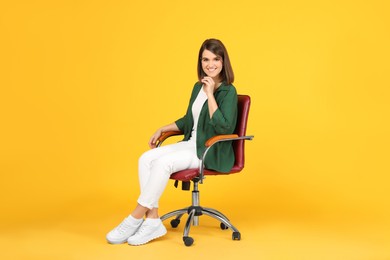 Photo of Young woman sitting in comfortable office chair on yellow background