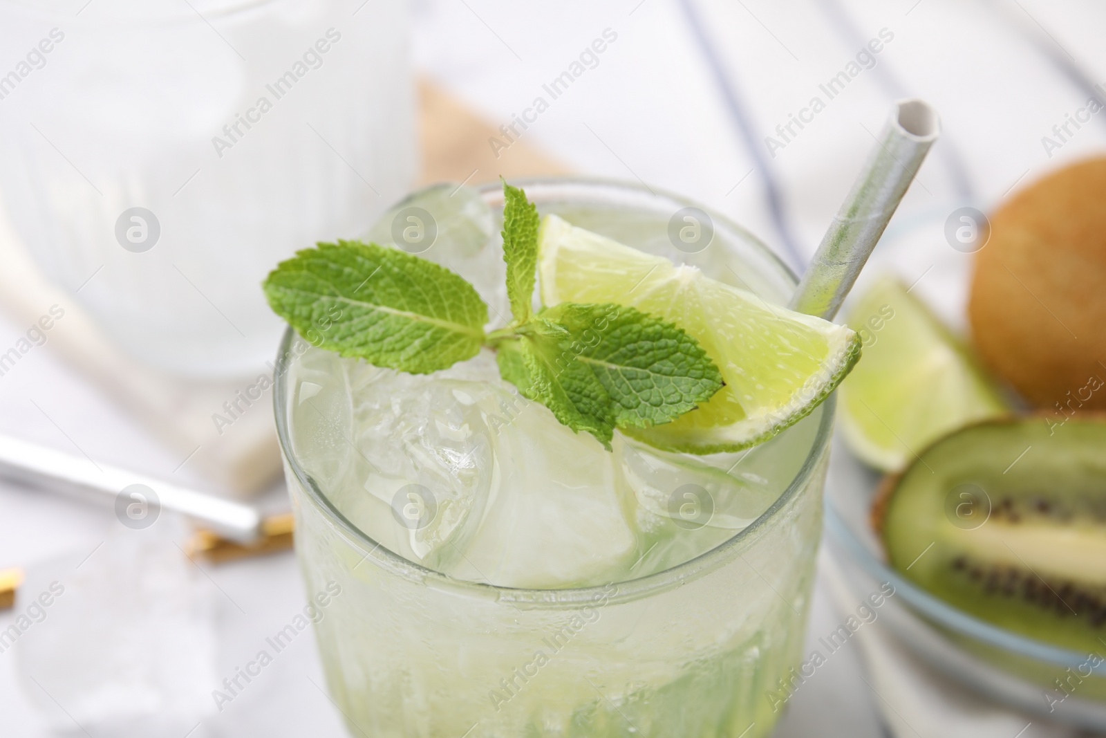 Photo of Glass of refreshing drink with lime and mint on white table, closeup