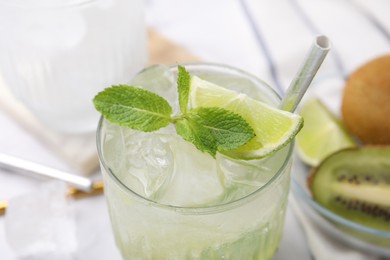 Photo of Glass of refreshing drink with lime and mint on white table, closeup