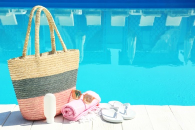 Beach accessories on wooden deck near swimming pool. Space for text