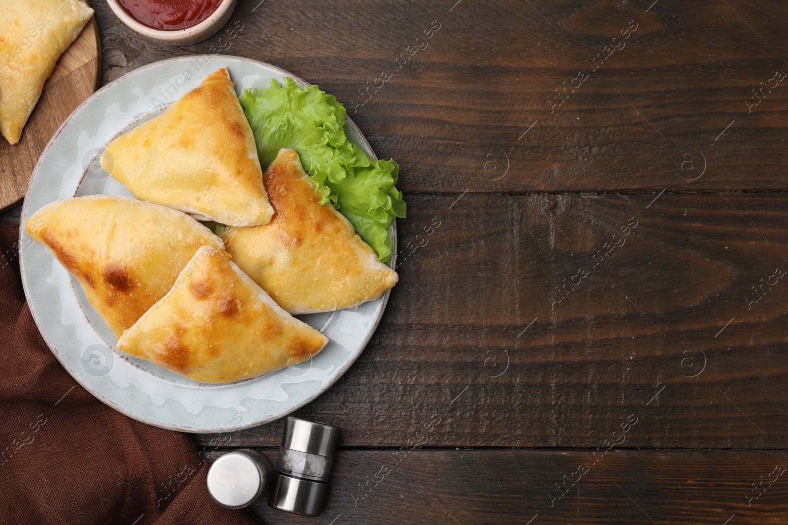 Photo of Delicious samosas and lettuce on wooden table, flat lay. Space for text