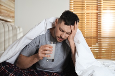 Photo of Man taking medicine for hangover in bedroom at home