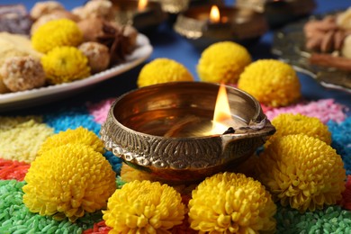 Photo of Diwali celebration. Diya lamps, colorful rangoli and chrysanthemum flowers on table, closeup