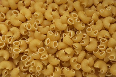 Photo of Pile of uncooked horns pasta as background, top view