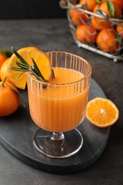 Photo of Delicious tangerine liqueur in glass and fresh fruits on grey table, closeup