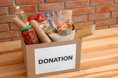 Photo of Donation box with food on table near brick wall