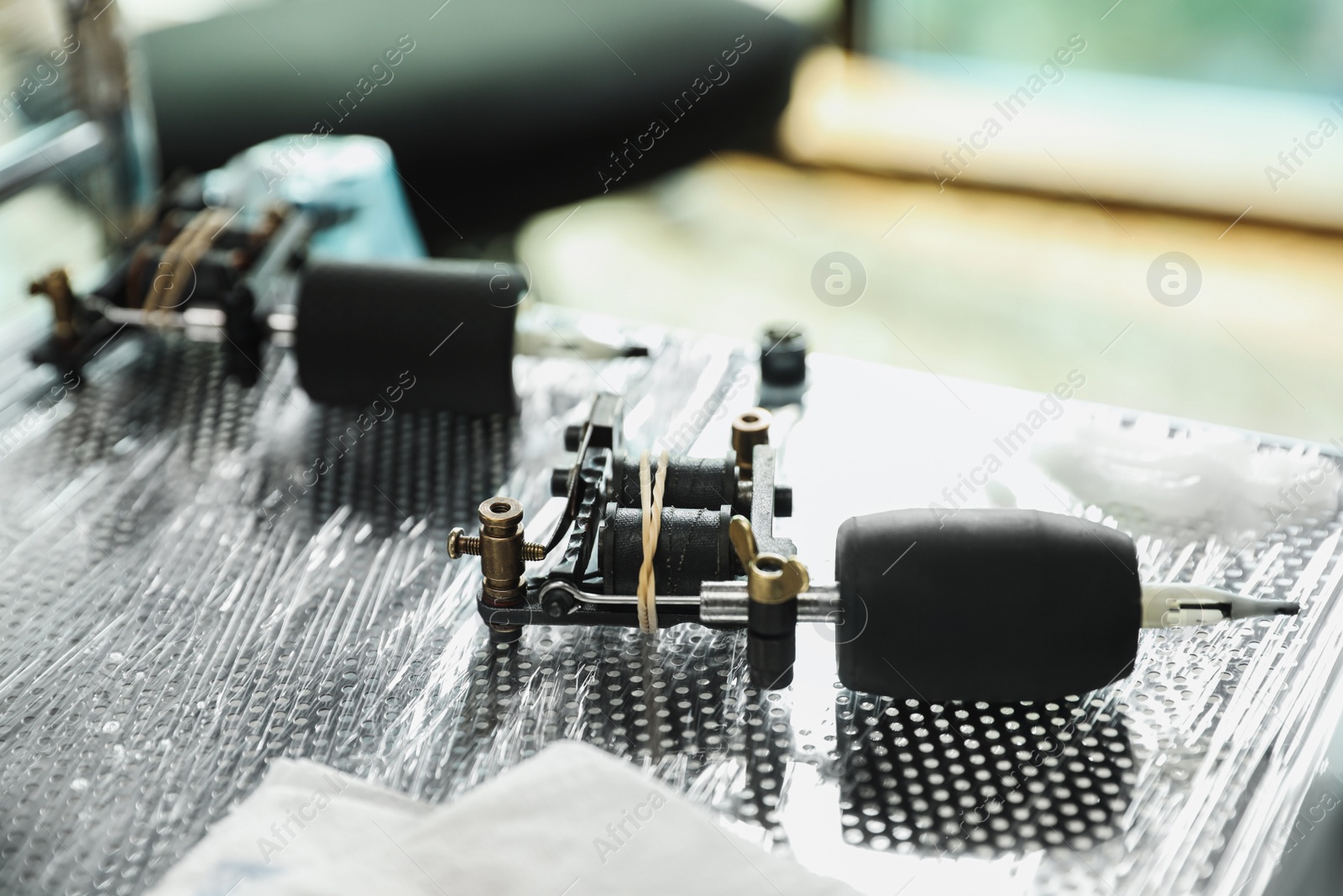 Photo of Modern professional tattoo machine on table in salon