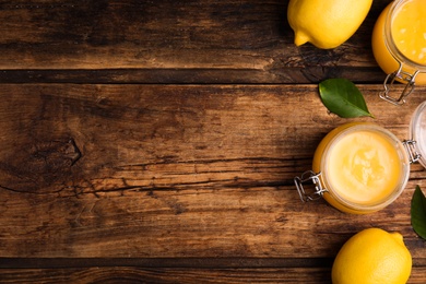 Delicious lemon curd and fresh fruits on wooden table, flat lay. Space for text