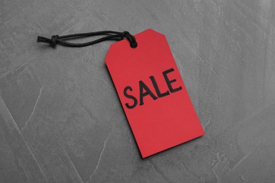 Photo of Red tag with word Sale on grey table, top view. Black Friday