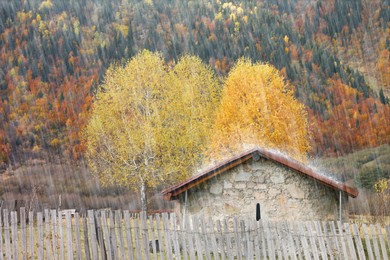 Picturesque view of house in mountains with forest on rainy day