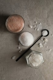 Photo of Different natural salt on grey textured table, flat lay