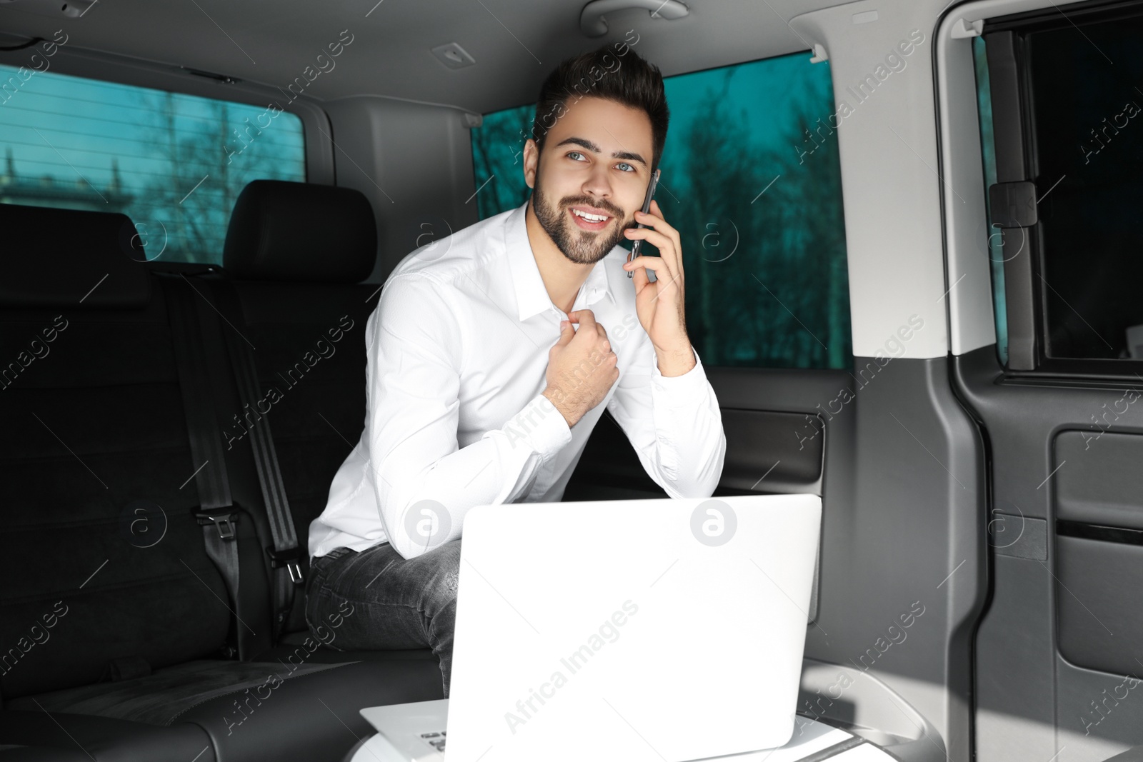 Photo of Young man talking on smartphone in modern car