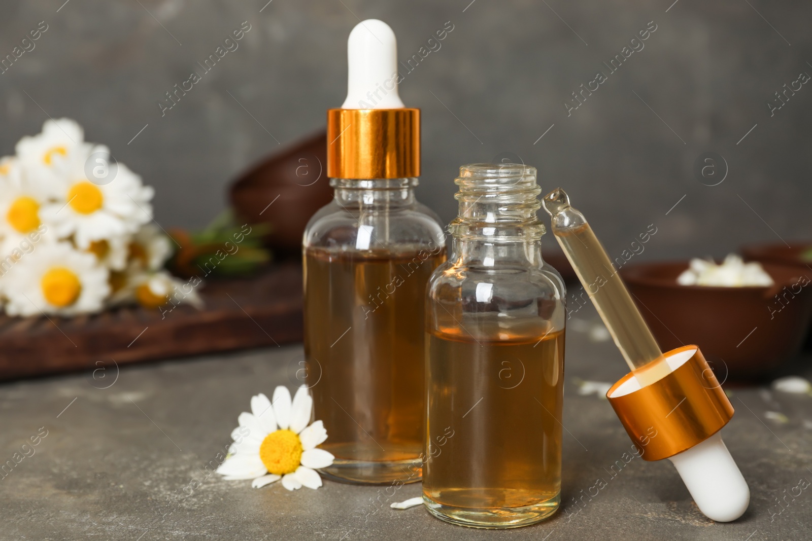 Photo of Composition with bottles of chamomile essential oil on table