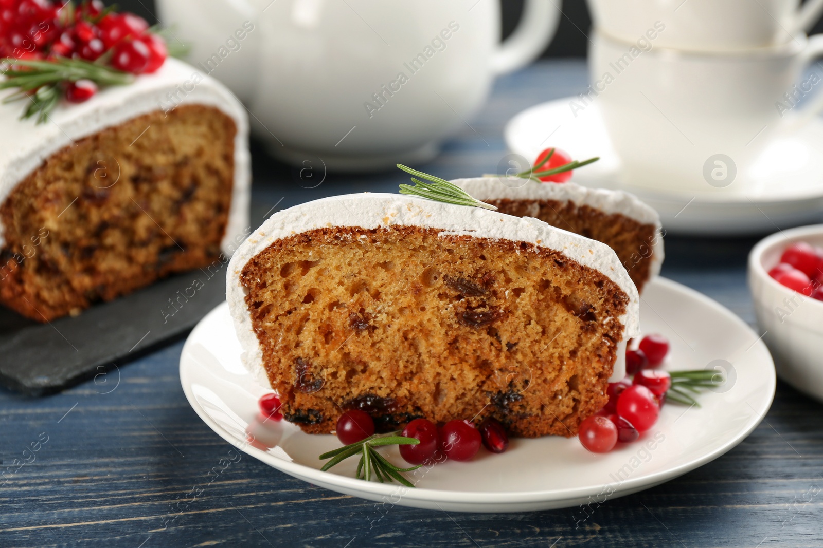 Photo of Traditional classic Christmas cake decorated with cranberries, pomegranate seeds and rosemary on wooden table