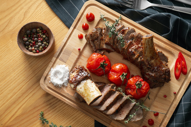 Photo of Delicious roasted ribs served on wooden table, flat lay