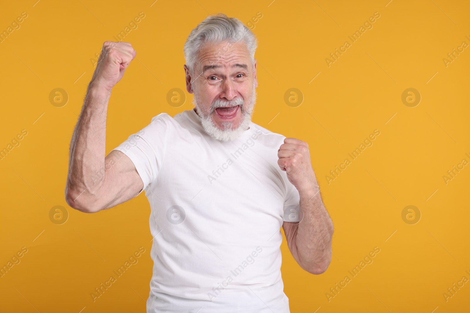 Photo of Portrait of surprised senior man on yellow background