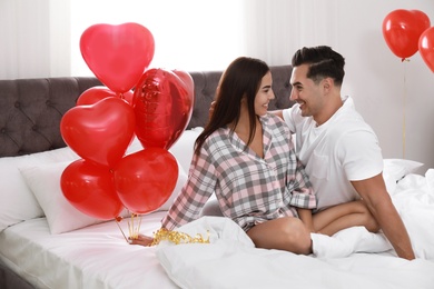 Beautiful couple with heart shaped balloons in bedroom