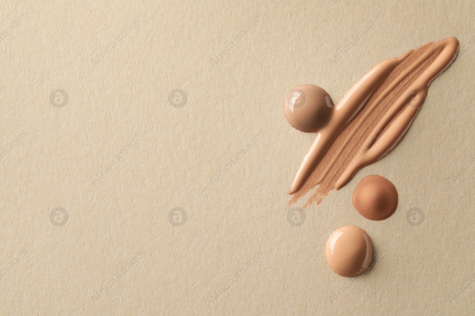 Photo of Samples of liquid skin foundations on beige background, top view. Space for text