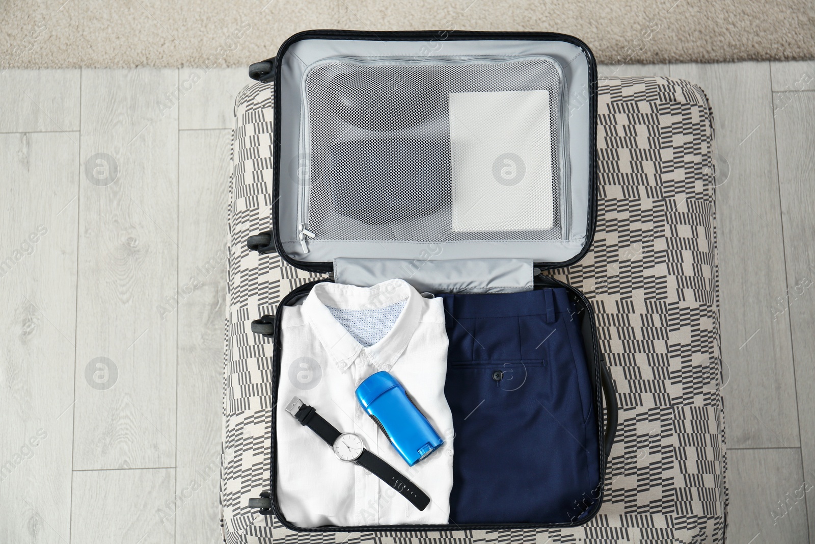 Photo of Deodorant in packed suitcase on floor, top view