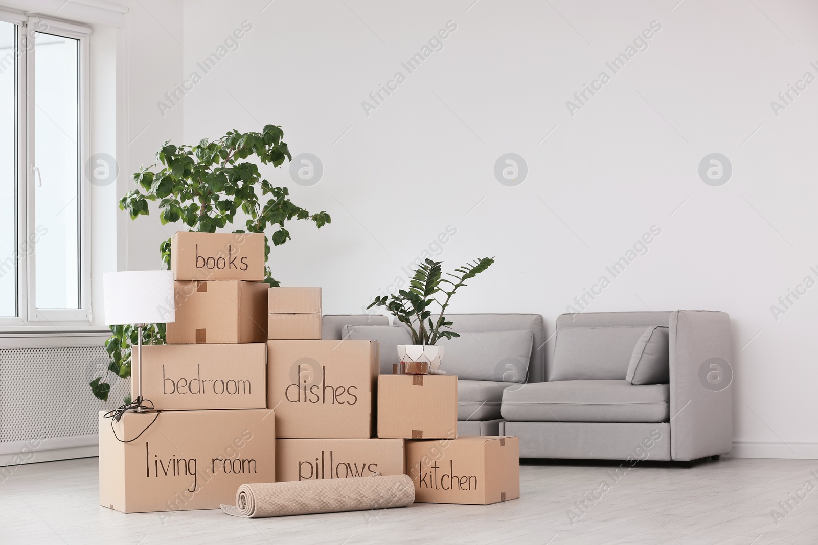 Photo of Pile of moving boxes and household stuff in living room