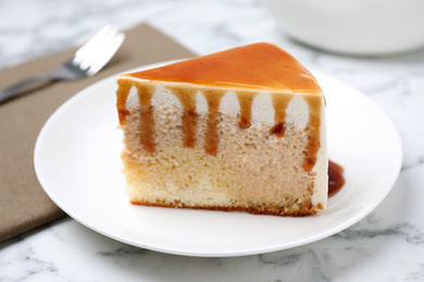 Photo of Slice of delicious cake with caramel sauce on white marble table