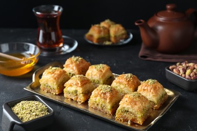 Photo of Delicious fresh baklava with chopped nuts served on dark textured table. Eastern sweets