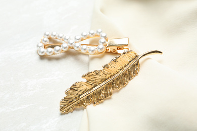 Photo of Beautiful gold hair clips and fabric on white table