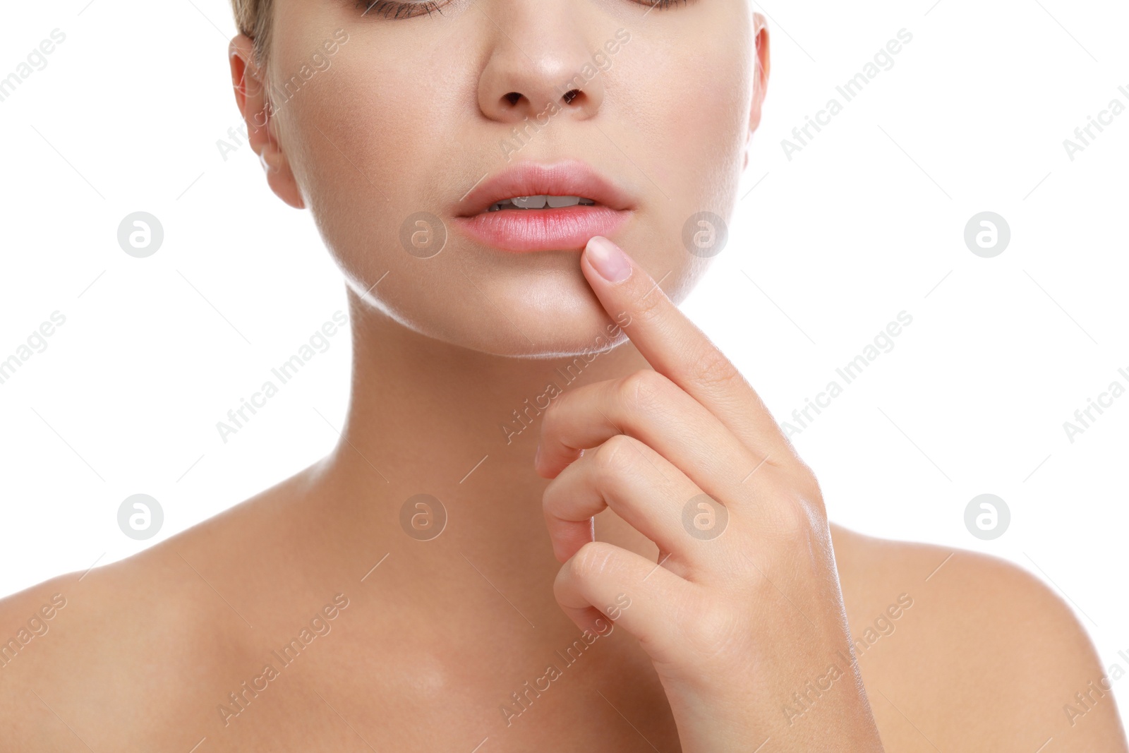 Photo of Young woman with cold sore touching lip against white background, closeup