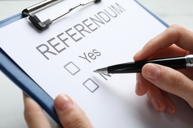 Woman with referendum ballot making decision on white background, closeup