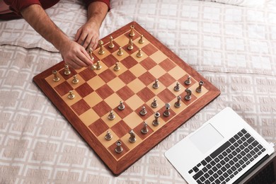 Man playing chess with partner through online video chat on bed, closeup