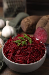 Grated red beet and dill in bowl on table, closeup