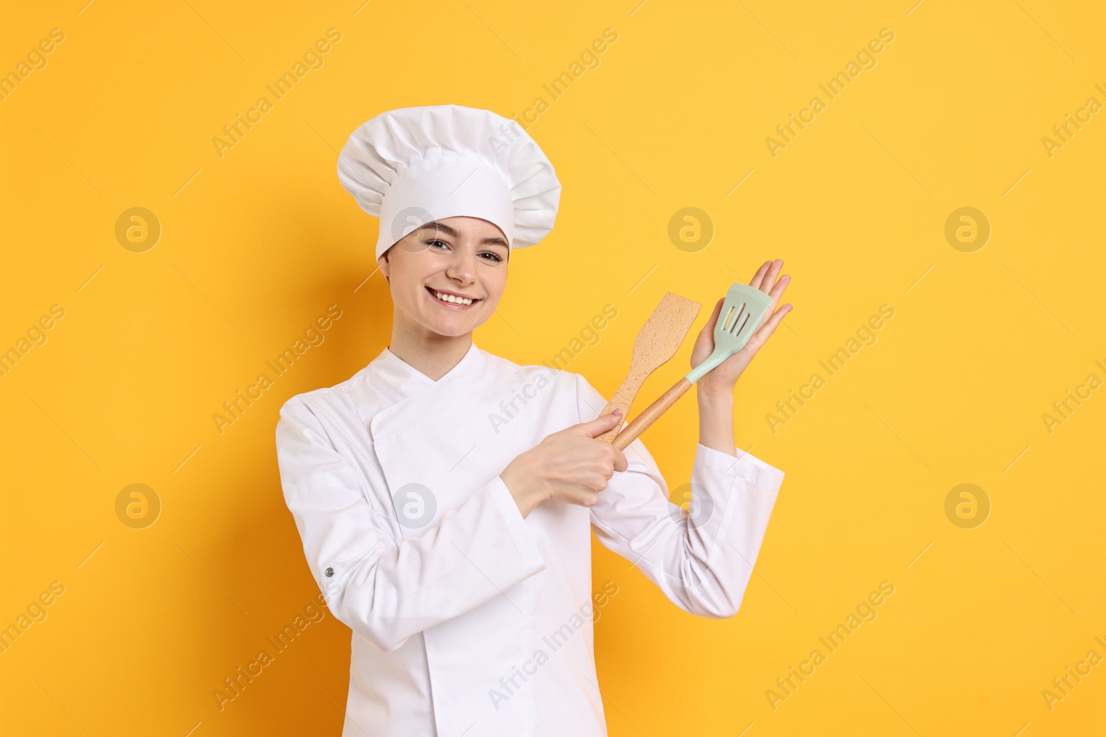 Photo of Professional chef with kitchen utensils on yellow background