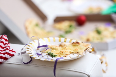 Photo of Plate with piece of pizza and streamer on sofa, closeup. Chaos after party