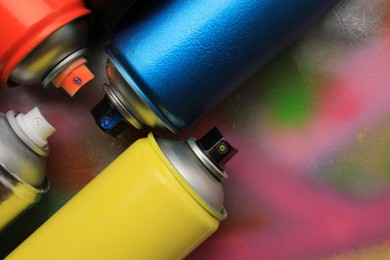 Cans of different graffiti spray paints on color background, flat lay