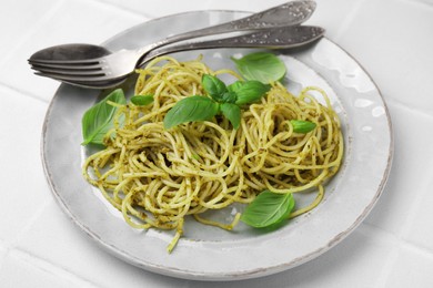 Photo of Delicious pasta with pesto sauce and basil served on white table, closeup
