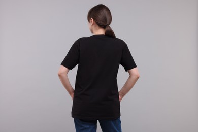 Woman in stylish black t-shirt light grey on background, back view