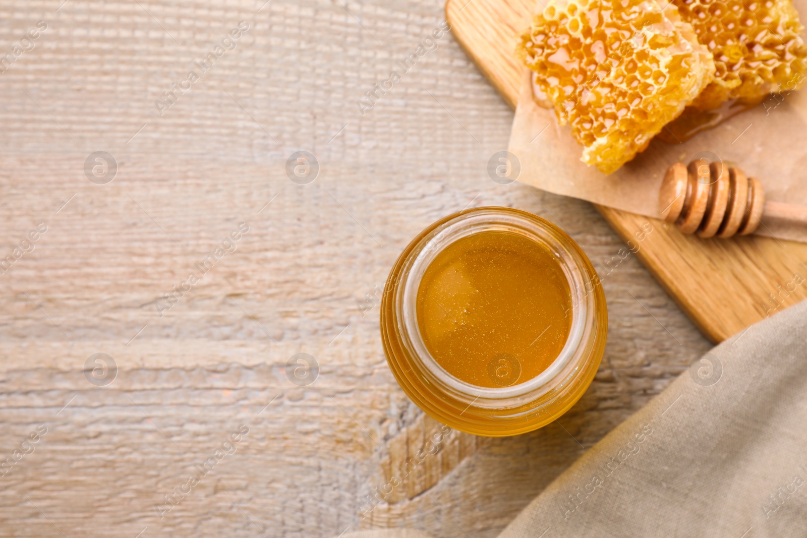 Photo of Tasty aromatic honey on wooden table, flat lay. Space for text