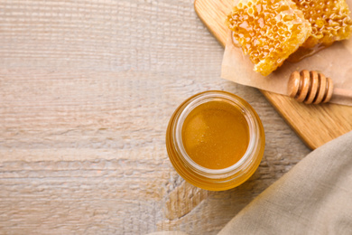 Photo of Tasty aromatic honey on wooden table, flat lay. Space for text