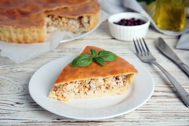 Slice of delicious meat pie with basil on white wooden table
